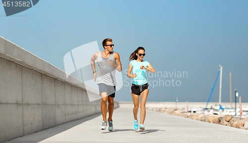 Image of couple with fitness tracker running along pier