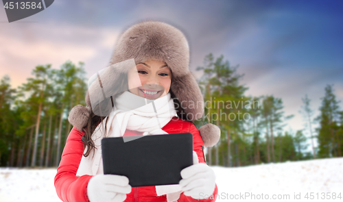 Image of woman in fur hat with tablet pc over winter forest