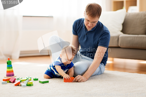 Image of happy father with baby son playing toys at home