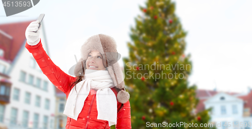 Image of woman taking selfie over christmas tree