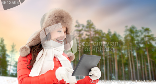 Image of woman in fur hat with tablet pc over winter forest