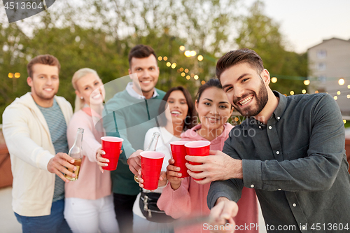 Image of friends with drinks taking selfie at rooftop party