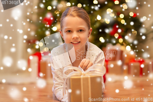 Image of smiling girl with christmas gift at home