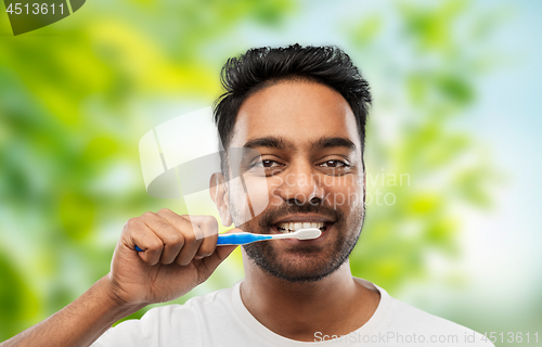 Image of indian man cleaning teeth over natural background