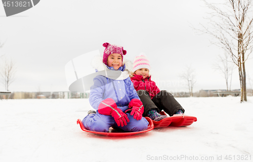 Image of happy little girls on sleds outdoors in winter