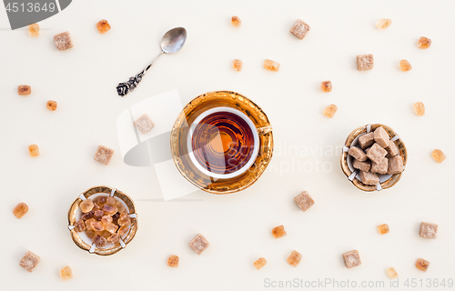 Image of Cup of tea and brown sugar on white background