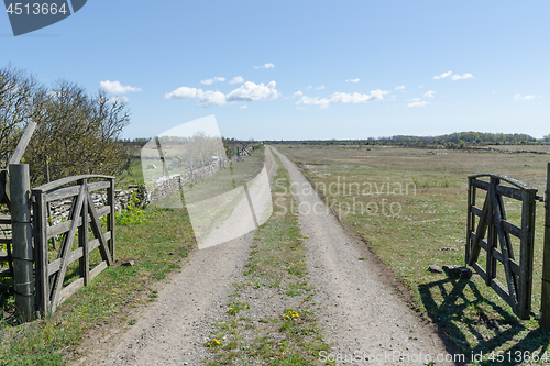 Image of Dirt road with wooden gates by a great plain grassland at the sw