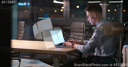 Image of man working on laptop in dark office