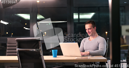 Image of man working on laptop in dark office