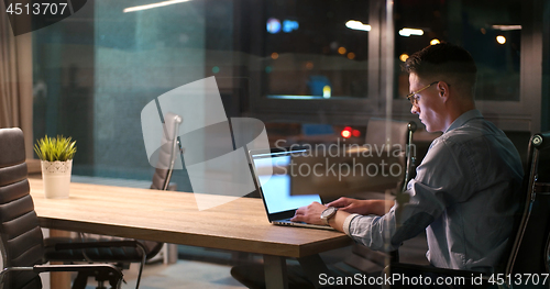 Image of man working on laptop in dark office