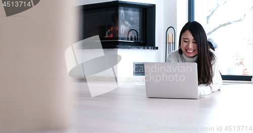 Image of Asian woman using laptop on floor