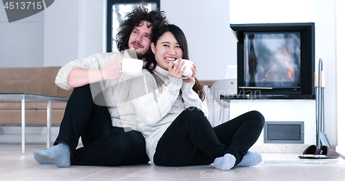 Image of multiethnic romantic couple  in front of fireplace