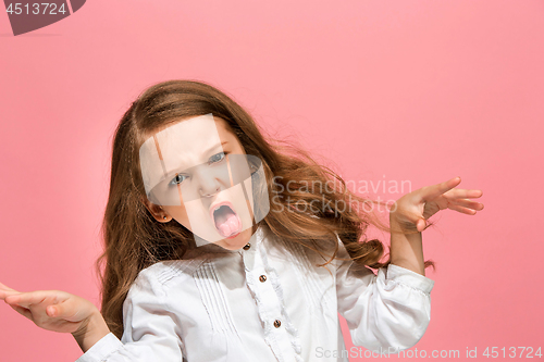 Image of Portrait of angry teen girl on a pink studio background