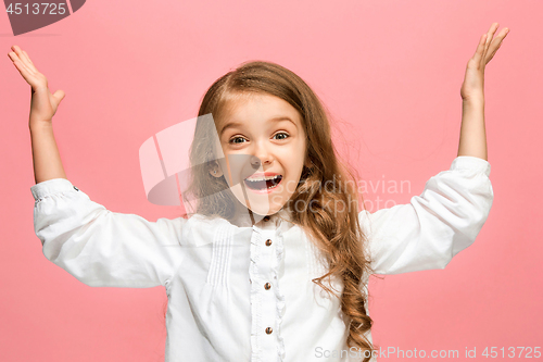 Image of The happy teen girl standing and smiling against pink background.