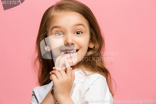 Image of The happy teen girl standing and smiling against pink background.