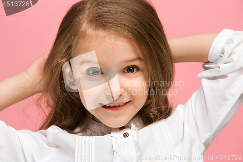 Image of The happy teen girl standing and smiling against pink background.