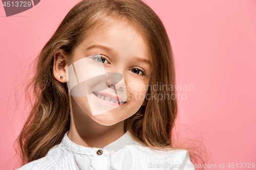 Image of The happy teen girl standing and smiling against pink background.