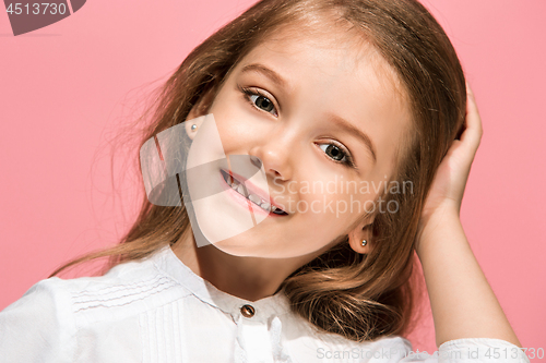 Image of The happy teen girl standing and smiling against pink background.