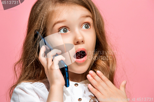 Image of The happy teen girl standing and smiling against pink background.