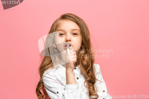Image of The young teen girl whispering a secret behind her hand over pink background