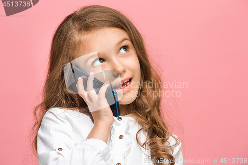 Image of The happy teen girl standing and smiling against pink background.