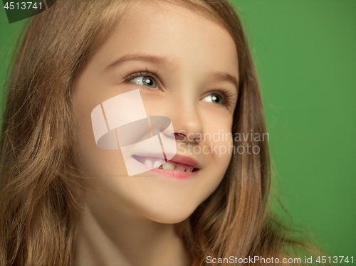 Image of The happy teen girl standing and smiling against green background.