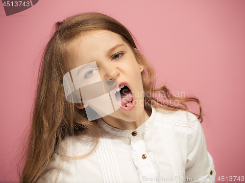 Image of Portrait of angry teen girl on a pink studio background