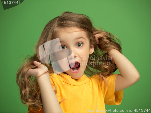 Image of The happy teen girl standing and smiling against green background.