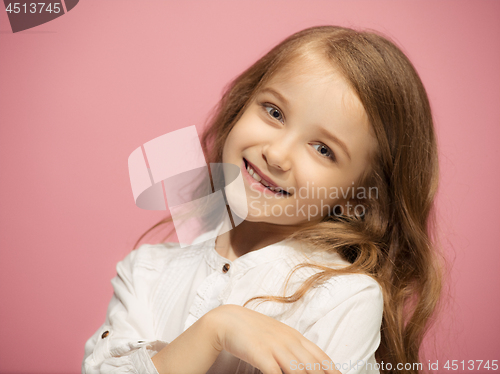 Image of The happy teen girl standing and smiling against pink background.