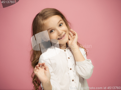 Image of The happy teen girl standing and smiling against pink background.