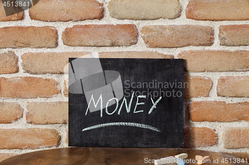 Image of Chalk board with the word MONEY drown by hand on wooden table on