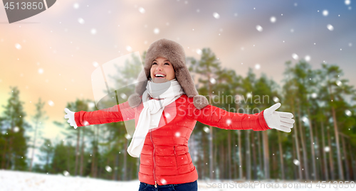 Image of happy woman in fur hat over winter forest and snow