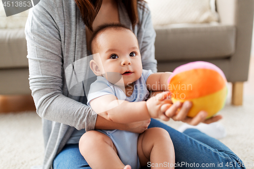 Image of mother and baby son playing with ball at home