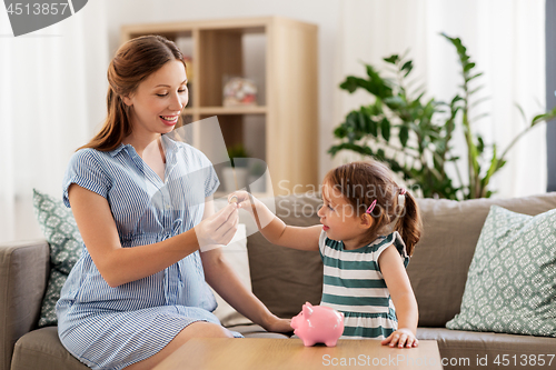 Image of pregnant mother and daughter with piggy bank