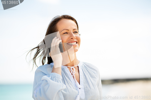 Image of happy woman calling on smartphone on summer beach