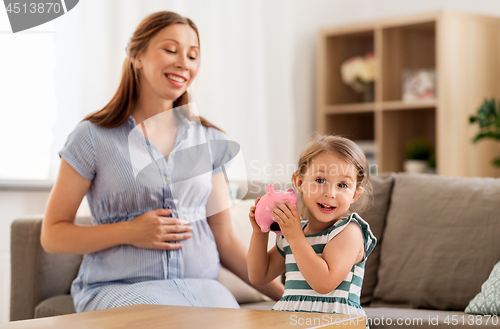 Image of pregnant mother and daughter with piggy bank