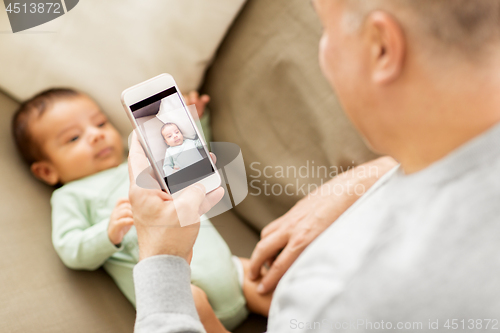 Image of father photographing baby by smartphone