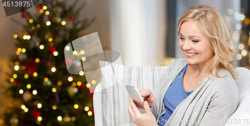 Image of smiling woman with smartphone texting on christmas