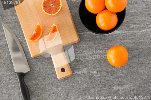 Image of close up of oranges and knife on cutting board