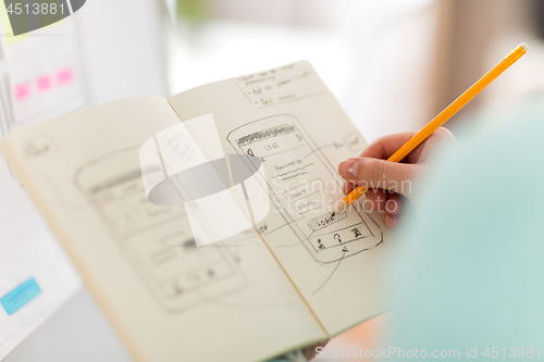 Image of ui designer with user interface sketch in notebook