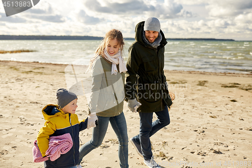 Image of happy family going to picnic on beach in autumn