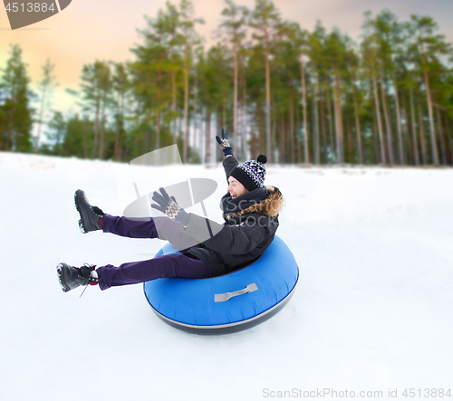 Image of happy young man sliding down hill on snow tube