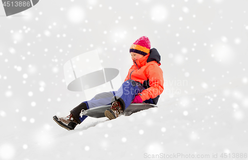 Image of happy little girl sliding down on sled in winter