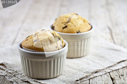 Image of Homemade fresh muffins on ceramic white bowls on linen napkin.