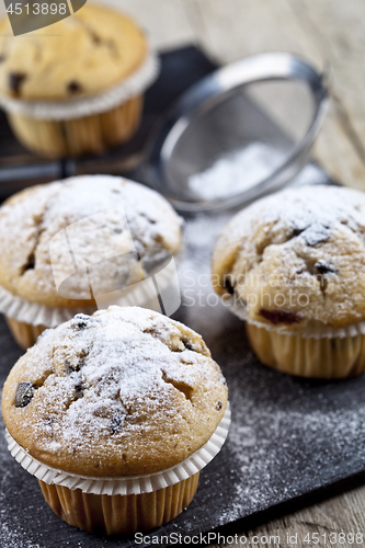 Image of Two fresh homemade muffins with sugar powder and metal strainer 