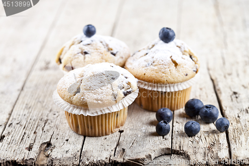 Image of Homemade fresh muffins with blueberries on rustic wooden table.