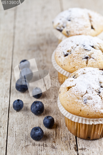 Image of Homemade fresh muffins with blueberries on rustic wooden table b