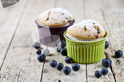 Image of Two homemade fresh muffins on ceramic green and purple bowls wit