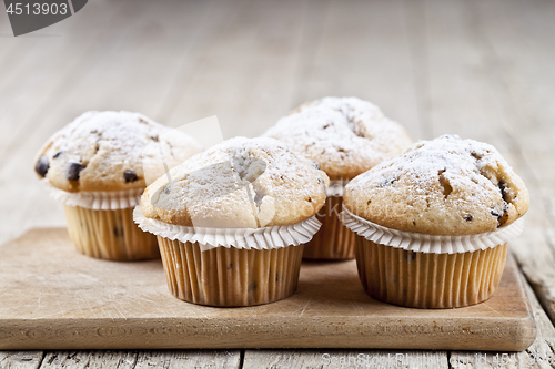 Image of Homemade fresh muffins with sugar powder on cutting board rustic