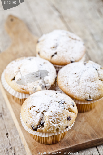 Image of Homemade fresh muffins with sugar powder on cutting board rustic